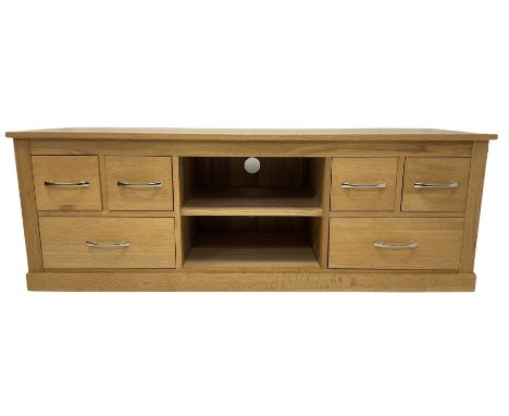 Modern oak television stand, fitted with one shelf, flanked by four short and two long drawers, raised on a plinth base 