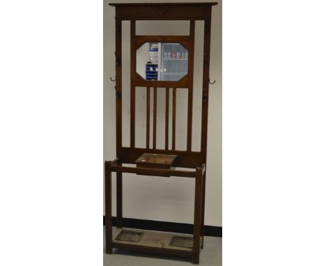 An oak hall stand,  octagonal mirror flanked by coat hooks, glove box and stick stand to base, circa 1930.