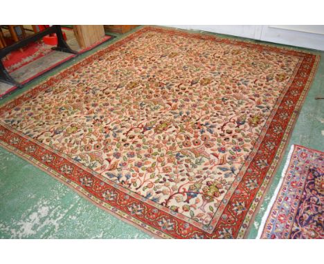 A large Persian carpet, the central field decorated with foliage in shades of yellow and green within a red border, approx 28