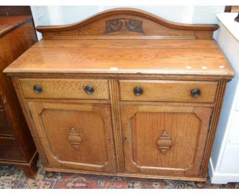 An oak sideboard, shaped and carved gallery, moulded top, two short drawers over panel doors to base (formerly a mirror back 