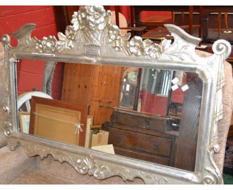 A Neo-Baroque silvered gesso mantel looking glass, the cresting centred by a fruiting basket trailing to a garland of flowers