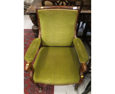 A 19th Century mahogany framed library chair with green velour upholstery, raised on turned and ringed front legs to brass ca