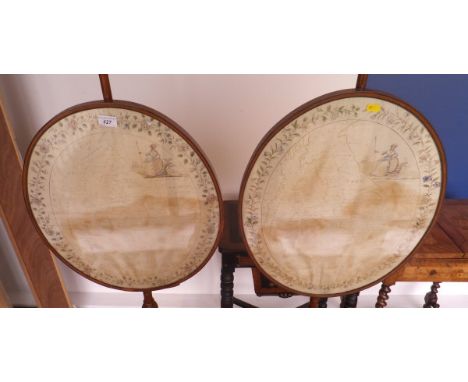 A pair of 19th Century mahogany pole screens in the Empire taste with oval painted silkwork maps of England and Wales, with a
