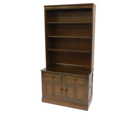 An Ercol dark elm dresser, the top with a carved frieze above four shelves, the base with two drawers above two panelled cupb