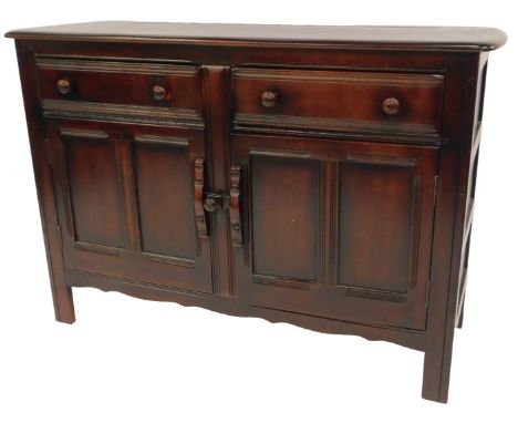 An Ercol dark elm sideboard, the rectangular top with a rounded edge above two drawers and two cupboards, on stiles, 84cm hig
