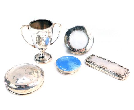 Five items of silver, comprising three silver dressing table jar lids, one with blue enamel set, a silver framed picture fram