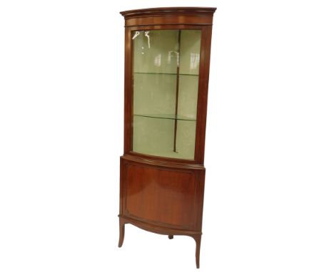 An Edwardian mahogany standing corner cabinet, the top with a moulded edge above a glazed door enclosing two glass shelves, t