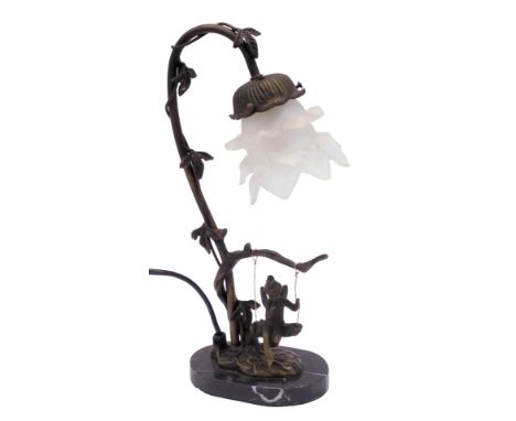 A table lamp, on a shaped oval marble foot, with an ebonised swing and child, with a floral glass shade, 38cm high. (AF)Buyer