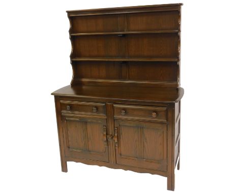 An Ercol dark elm dresser, the top with two shelves, the base with a rounded edge above two drawers and two panelled cupboard