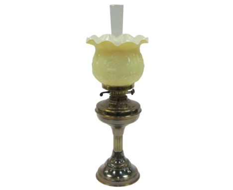 An early 20thC brass oil lamp, with a chimney and amber case glass frill shade moulded with stylised flowers, 59cm high. 