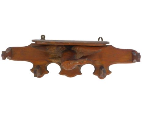 A late 19th/early 20thC oak Black Forest wall shelf, the shelf above a carved figure of an eagle, with four coat hooks, 67cm 