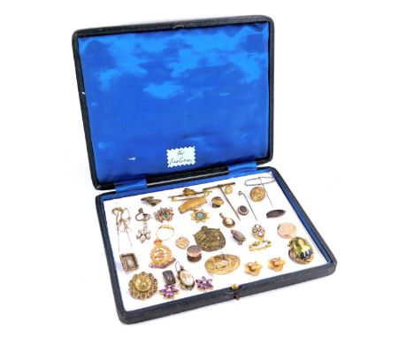A presentation case containing stick pins and brooches, including Royal Army Medical Corps enamel badge, leaf moulded earring