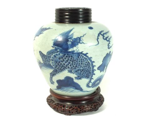 Chinese ginger jar, painted with a dragon in blue, Kangxi period 1662 - 1722, with wood stand and cover. The vase stands 23cm