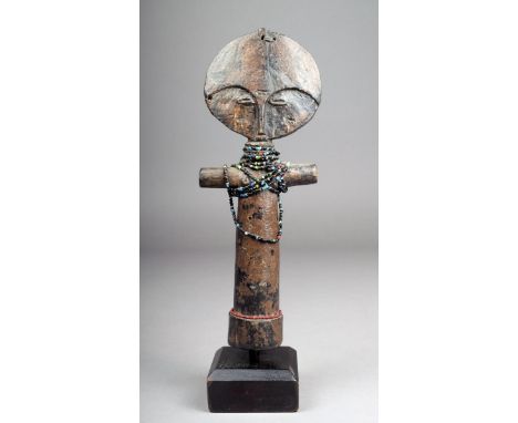 An Ashanti Akuba doll Ghana the disc head with carved facial features with a point terminal the reverse with incised decorati
