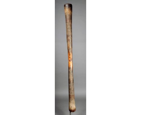 A Dogon large wooden pestle Mali of hour glass shape with incised bands 141cm long on a stand. (2)  Provenance Ian Auld Londo