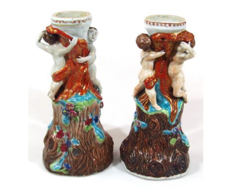 A pair of 20thC majolica style lamp bases, each cherubic and naturalistic stem, profusely polychrome decorated predominantly 