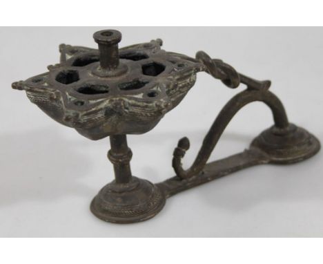 A Middle Eastern metal candlestick, with floral pierced dish holder on an entwined double domed base, 17cm wide.