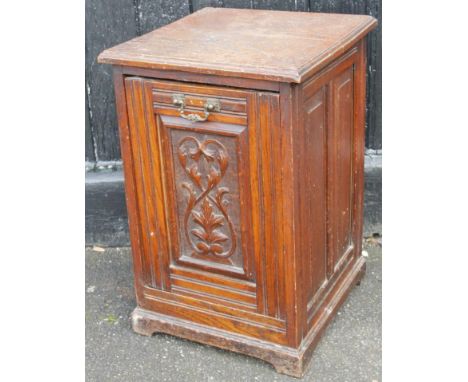 A late 19thC carved walnut coal purdonium, the overhanging square top raised above a carved panelled door, hinging to reveal 