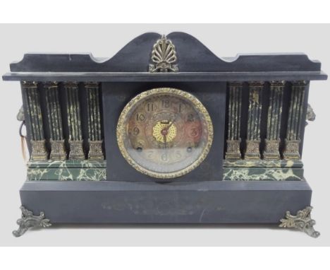 An early 20thC ebonised temporal mantel clock, centred by a 13cm dia. Arabic dial surmounted by a shell and flanked by four m