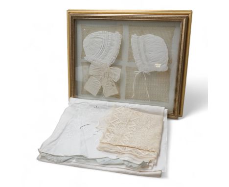 A collection of lace and textiles comprising a large cutwork tablecloth, a lace cloth, framed baby bonnets and 8 lace mats (f