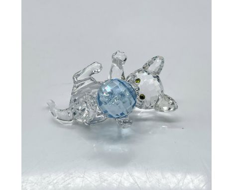 Clear crystal figure with melon-colored eyes lying adorably on its back with open paws to play with its blue ball of wool. Sw