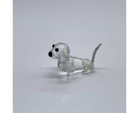 A clear crystal figure of a tiny dog with floppy ears. Black crystal eyes and nose, and a braided metal tail. Swarovski Silve