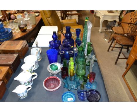 A collection of various coloured glassware to include shaped decanter, a tall green glass vase, various blue vases, handkerch