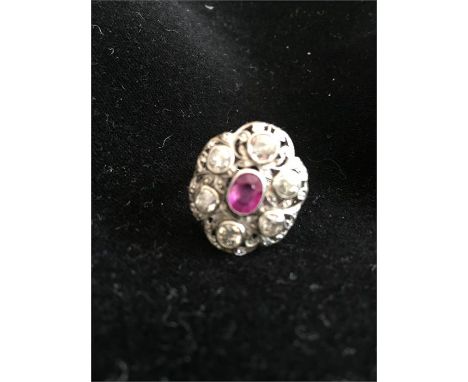 An antique white gold ring with diamonds and central ruby stone