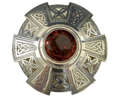 the central faceted orange stone set in a pierced and engraved brooch decorated with Celtic, foliate and geometric designs, 9