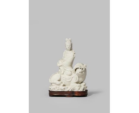 A CHINESE BLANC DE CHINE FIGURE OF GUANYIN LATE QING DYNASTY Wearing flowing robes, seated on the back of a Buddhist lion dog