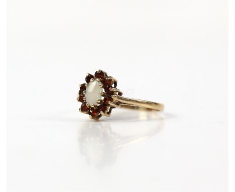 Opal and garnet cluster ring, oval cabochon cut opal, with a surround of round cut garnets, mounted in 9 ct yellow gold, ring