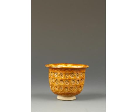 the everted rim above a deep body with three registers of impressed circular motifs, the conical foot unglazed, Tang Dynasty,