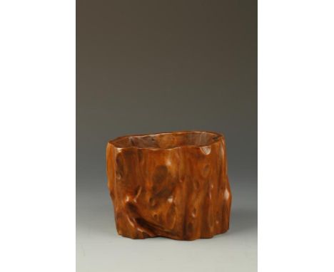 A CHINESE HUANGYANGMU (BOXWOOD) TRUNK-FORM BRUSH POT, of asymmetric form carved from a single piece of wood, with a recessed 