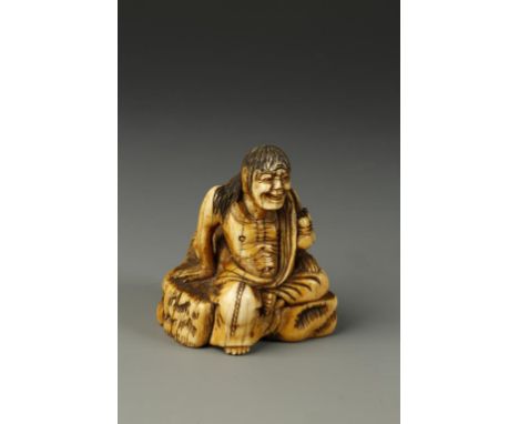 A JAPANESE IVORY FIGURE NETSUKE the emaciated ascetic seated on rocks with one leg pendant, late Edo - early Meiji period, 5c