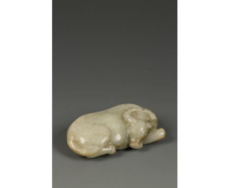 A CHINESE CELADON JADE RECUMBENT BUFFALO, the animal lying flat with its' head turned to the right, Ming Dynasty, 9.5cm long.