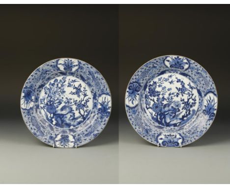 A PAIR OF CHINESE BLUE AND WHITE CHARGERS decorated with birds perched on rocks in garden landscapes, within borders with ruy