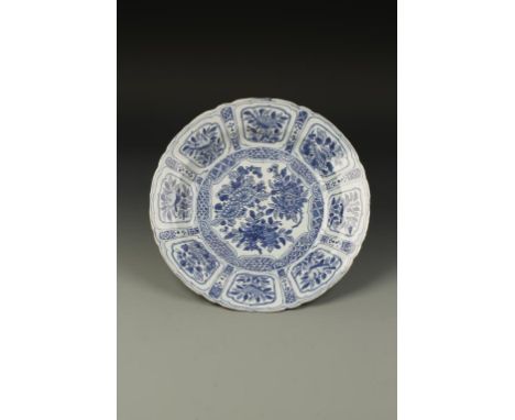 A CHINESE BLUE AND WHITE KRAAK DISH, the central well decorated with chrysanthemums and other flowers within an ogee-panel bo