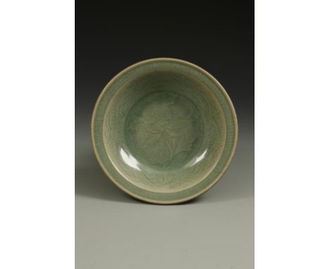 A CHINESE LONGQUAN CELADON DISH, the centre with a carved flower design within a scroll cavetto and broad rim, the body gentl