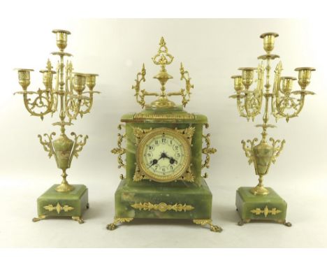 A Victorian onyx clock garniture, with gilt metal five branch candlesticks on vase shaped column and square base with four li