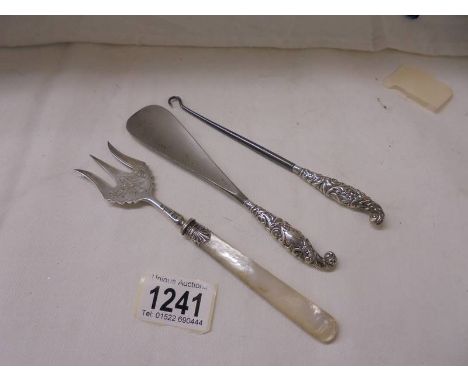 A silver fork with mother of pearl handle together with a silver handled shoe horn and button hook.&nbsp;