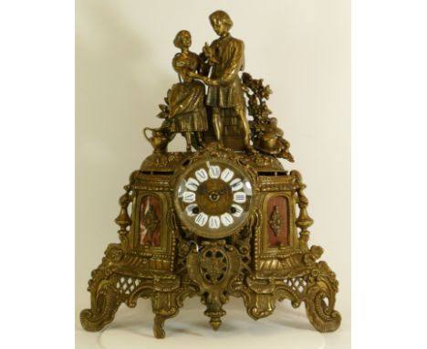A gilt brass Ormolu style mantel clock, the scrolling floral case with inset marble panels housing a manual movement striking