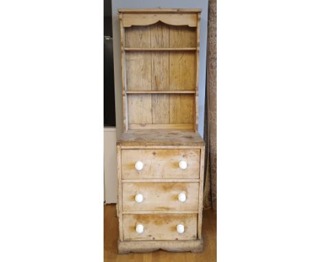 A stripped pitch pine dresser, circa late 19th century, having carved plate rack, above three graduated drawers with ceramic 