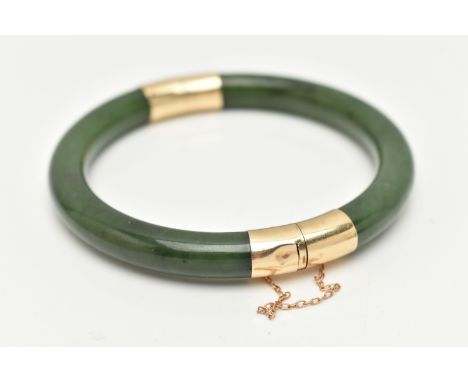 A NEPHRITE JADE BANGLE, with fittings to the hinge and clasp, safety chain attached, clasp stamped 14k, approximate inner dia