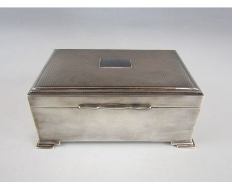 A George VI silver cigarette box, having a subtly domed, terraced and engine-turned lid centered by a vacant cartouche, on co