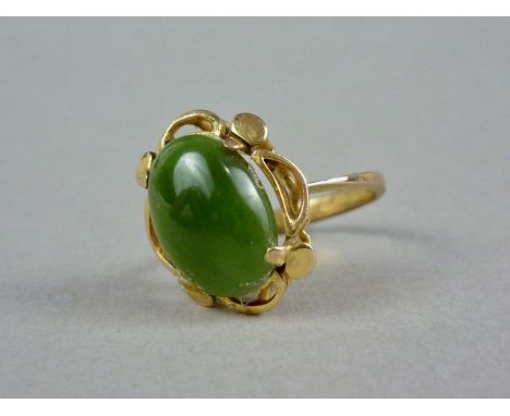 A jade and yellow-metal cocktail ring, the cabochon claw set within a stylized pelleted and cusped petal-form frame, above an