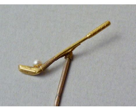 A yellow metal novelty stick pin modelled in the form of a golf club with seed pearl golf ball, tests as gold