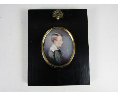 A mid 19th Century portrait miniature of a young boy, depicted in profile with blond curls and green silk coat, label verso r