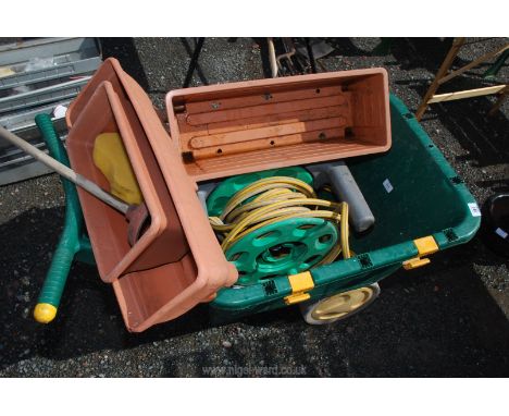 A plastic wheelbarrow, 3 plastic planters and a hose on reel.