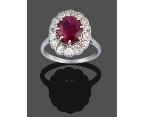 A Ruby and Diamond Cluster Ring, the oval cut ruby in a white claw setting within a border of old cut diamonds in rubbed over