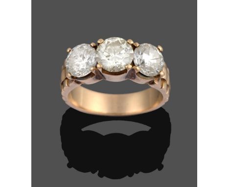 A Diamond Three Stone Ring, the graduated round brilliant cut diamonds in yellow claw settings, to a textured shoulder plain 